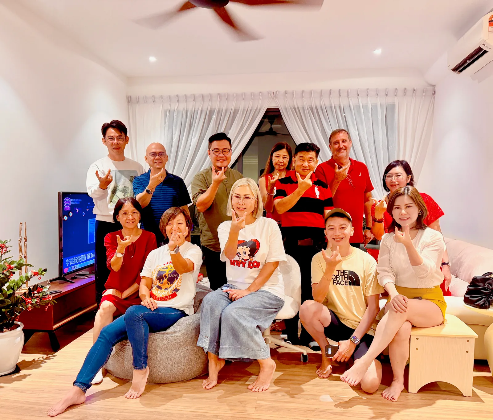 Eve Ang’s team at a house gathering making finger hearts